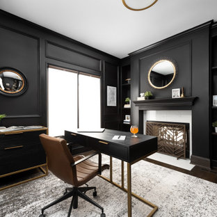 Foto de despacho boiserie, tradicional renovado, grande, boiserie, con paredes negras, suelo de madera oscura, chimenea de doble cara, marco de chimenea de piedra, escritorio independiente y boiserie