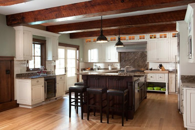 Large island style u-shaped light wood floor eat-in kitchen photo in Wilmington with an undermount sink, raised-panel cabinets, white cabinets, marble countertops, white backsplash, subway tile backsplash, stainless steel appliances and an island