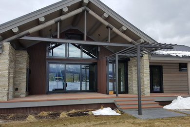 Huge modern one-story wood house exterior idea in Other with a metal roof