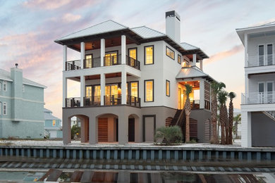 Mid-sized beach style white three-story stucco house exterior photo in Other with a hip roof and a metal roof