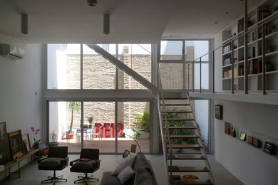 Ejemplo de biblioteca en casa tipo loft escandinava grande con paredes blancas, suelo de cemento, televisor independiente y suelo gris