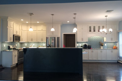 Enclosed kitchen - large transitional l-shaped brown floor and dark wood floor enclosed kitchen idea in Boston with an undermount sink, recessed-panel cabinets, granite countertops, ceramic backsplash, stainless steel appliances, an island, white cabinets, blue backsplash and gray countertops