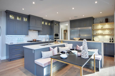 Transitional l-shaped light wood floor eat-in kitchen photo in Calgary with an undermount sink, shaker cabinets, blue cabinets, multicolored backsplash, stainless steel appliances and white countertops