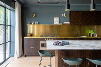 Inspiration for a mid-sized midcentury galley eat-in kitchen in London with an integrated sink, flat-panel cabinets, dark wood cabinets, marble benchtops, metallic splashback, stainless steel appliances, medium hardwood floors, with island, brown floor and white benchtop.