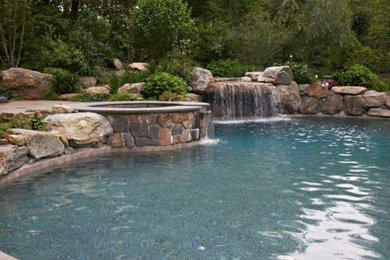 Example of a mid-sized transitional backyard stone and custom-shaped natural hot tub design in Boston