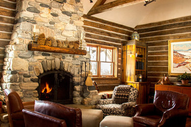 Example of a mid-sized mountain style dark wood floor living room design in Other with brown walls, a two-sided fireplace and a stone fireplace