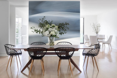 Cette photo montre une grande salle à manger ouverte sur le salon tendance avec un mur blanc et parquet clair.