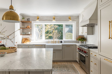 Kitchen - transitional l-shaped medium tone wood floor and brown floor kitchen idea in Seattle with shaker cabinets, an island, a farmhouse sink, beige cabinets, white backsplash, stone slab backsplash, stainless steel appliances and white countertops