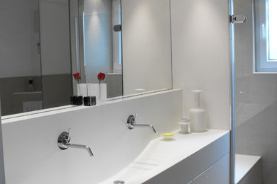Modernes Badezimmer En Suite mit flächenbündigen Schrankfronten, weißen Schränken, Eckbadewanne, bodengleicher Dusche, Wandtoilette mit Spülkasten, grauen Fliesen, Keramikfliesen, grauer Wandfarbe, Keramikboden, Trogwaschbecken und Mineralwerkstoff-Waschtisch in Stuttgart