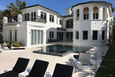 Inspiration for a modern backyard stone and rectangular infinity hot tub remodel in Miami