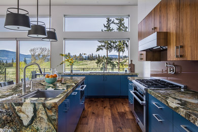 Example of a trendy dark wood floor and brown floor kitchen design in San Luis Obispo with a single-bowl sink, flat-panel cabinets, blue cabinets, brown backsplash, glass sheet backsplash, stainless steel appliances, an island and multicolored countertops
