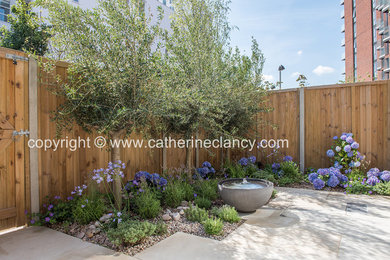 Photo of a small contemporary partial sun garden in London with a water feature and natural stone paving.