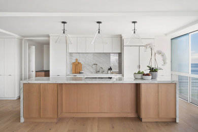 Inspiration for a mid-sized scandinavian single-wall open plan kitchen in San Diego with an undermount sink, shaker cabinets, light wood cabinets, quartz benchtops, grey splashback, engineered quartz splashback, panelled appliances, light hardwood floors, with island and grey benchtop.