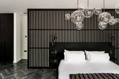 Inspiration for a large contemporary master bedroom in London with black walls, dark hardwood floors and grey floor.