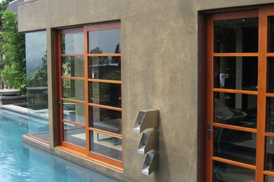 Example of a huge minimalist backyard concrete paver and custom-shaped infinity pool design in Los Angeles
