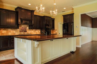 Inspiration for a large craftsman galley marble floor kitchen remodel in Tampa with an undermount sink, dark wood cabinets, wood countertops, beige backsplash, black appliances and an island