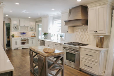 Inspiration for a large country u-shaped eat-in kitchen in New York with an undermount sink, raised-panel cabinets, white cabinets, quartz benchtops, white splashback, stainless steel appliances, multiple islands and brown floor.