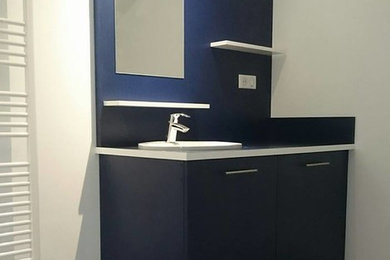 Idée de décoration pour une petite salle d'eau minimaliste avec un placard à porte affleurante, des portes de placard bleues, une vasque, un plan de toilette en stratifié et un plan de toilette blanc.