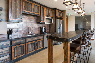 Eat-in kitchen - large rustic single-wall concrete floor and gray floor eat-in kitchen idea in Other with an undermount sink, recessed-panel cabinets, distressed cabinets, quartzite countertops, metallic backsplash, metal backsplash, stainless steel appliances, an island and black countertops