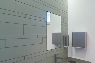 Mittelgroße Industrial Gästetoilette mit Wandtoilette, grünen Fliesen, Steinfliesen, weißer Wandfarbe, Keramikboden, Beton-Waschbecken/Waschtisch und integriertem Waschbecken in Köln