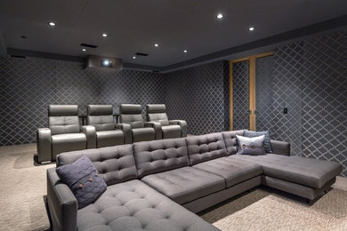 This is an example of a large contemporary enclosed home theatre in Orange County with grey walls, carpet and a projector screen.