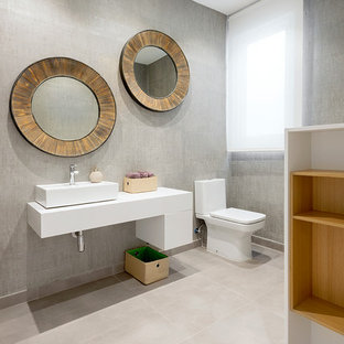 Esempio di un bagno di servizio contemporaneo di medie dimensioni con WC a due pezzi, pareti grigie, pavimento con piastrelle in ceramica, ante lisce, ante bianche, lavabo a bacinella e pavimento beige