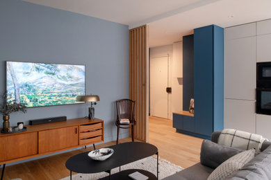 Réalisation d'une salle de séjour minimaliste de taille moyenne et ouverte avec un mur gris, parquet clair, aucune cheminée, un téléviseur fixé au mur et un sol beige.