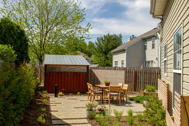 Small modern backyard full sun xeriscape in New York with with privacy feature and concrete pavers for spring.