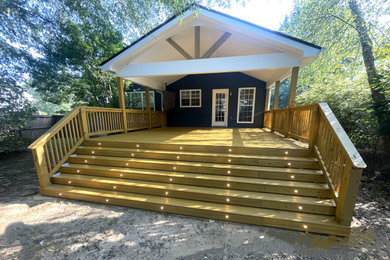 Large elegant backyard ground level wood railing deck photo in Atlanta with a roof extension