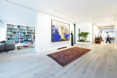 This is an example of a large contemporary foyer in Valencia with white walls, light hardwood floors, a single front door and a white front door.