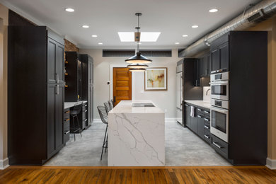 Example of a mid-sized minimalist galley gray floor eat-in kitchen design in Cincinnati with flat-panel cabinets, dark wood cabinets, quartz countertops, stainless steel appliances, an island and white countertops
