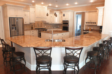 Elegant u-shaped dark wood floor and brown floor eat-in kitchen photo in Cleveland with a drop-in sink, raised-panel cabinets, white cabinets, granite countertops, beige backsplash, mosaic tile backsplash, stainless steel appliances and an island