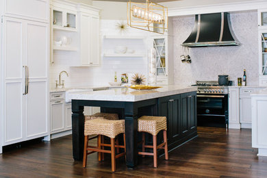 Open concept kitchen - mid-sized transitional u-shaped dark wood floor open concept kitchen idea in Raleigh with a farmhouse sink, recessed-panel cabinets, white cabinets, granite countertops, gray backsplash, stone slab backsplash, paneled appliances and an island