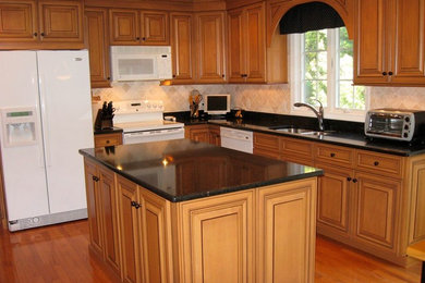 Mid-sized elegant l-shaped medium tone wood floor kitchen photo in Providence with an undermount sink, recessed-panel cabinets, brown cabinets, quartz countertops, beige backsplash, stone tile backsplash, white appliances and an island