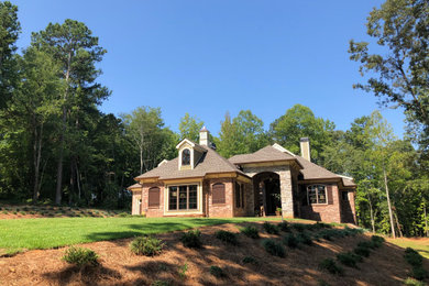 Example of a mid-sized cottage red two-story brick house exterior design with a hip roof and a shingle roof
