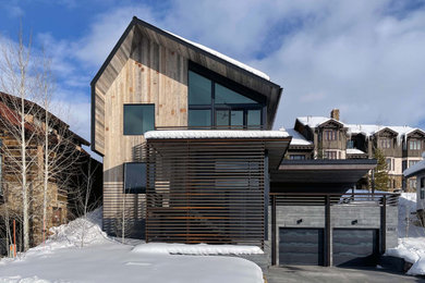 Modelo de fachada de casa negra rústica de tres plantas con revestimiento de madera, tejado a dos aguas y tejado de metal
