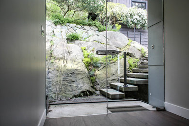 Inspiration for a large modern medium tone wood floor and brown floor entryway remodel in Vancouver with gray walls and a glass front door