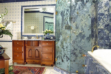 Design ideas for a large traditional master bathroom in Miami with raised-panel cabinets, brown cabinets, a drop-in tub, an alcove shower, a one-piece toilet, blue tile, porcelain tile, blue walls, porcelain floors, a drop-in sink, granite benchtops, white floor and a hinged shower door.