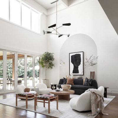 Example of a large trendy open concept medium tone wood floor and vaulted ceiling living room design in Dallas with white walls and a concealed tv