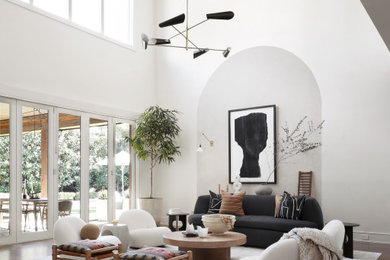 ダラスにあるラグジュアリーな広いコンテンポラリースタイルのおしゃれなLDK (白い壁、内蔵型テレビ、黒いソファ、白い天井、無垢フローリング、三角天井) の写真