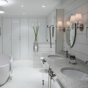 Mid-sized cottage master concrete floor and white floor freestanding bathtub photo with flat-panel cabinets, white cabinets, a wall-mount toilet, white walls, an undermount sink and terrazzo countertops