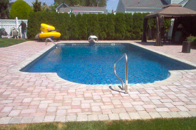 Inspiration for a mid-sized indoor rectangular pool in New York with brick pavers.