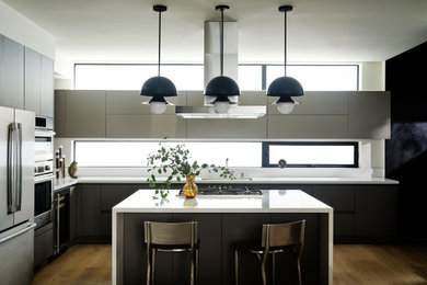Modelo de cocina contemporánea con armarios con paneles lisos, puertas de armario grises, una isla y encimeras blancas