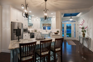 Eat-in kitchen - transitional single-wall dark wood floor eat-in kitchen idea in Other with a farmhouse sink, white cabinets, white backsplash, stainless steel appliances, an island, recessed-panel cabinets, ceramic backsplash and granite countertops