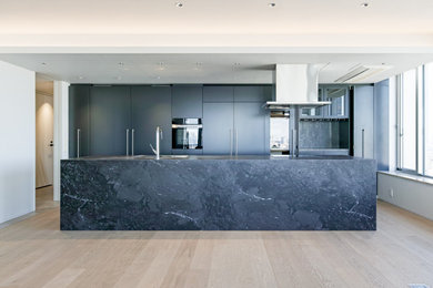 Diseño de cocina minimalista abierta con puertas de armario grises, encimera de azulejos, una isla y encimeras negras