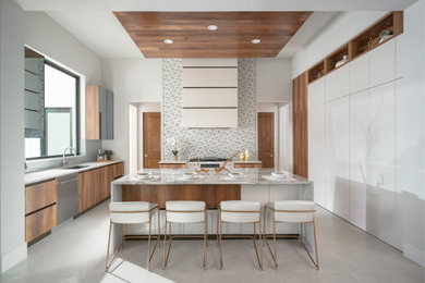 Example of a trendy u-shaped gray floor kitchen design in Houston with an undermount sink, flat-panel cabinets, medium tone wood cabinets, stainless steel appliances, an island and gray countertops