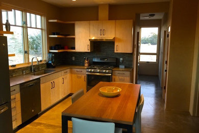 Small contemporary l-shaped eat-in kitchen in Albuquerque with a single-bowl sink, flat-panel cabinets, light wood cabinets, quartz benchtops, grey splashback, glass tile splashback, stainless steel appliances and concrete floors.