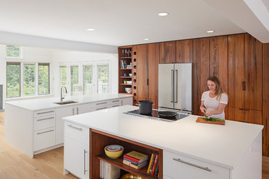 Inspiration for a large modern u-shaped eat-in kitchen in Philadelphia with flat-panel cabinets, dark wood cabinets, stainless steel appliances, light hardwood floors, with island, an undermount sink, quartz benchtops, beige floor and white benchtop.