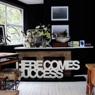Design ideas for an industrial home studio in Mexico City with black walls, painted wood floors, a standard fireplace, a brick fireplace surround and a freestanding desk.