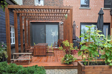 Diseño de terraza planta baja actual grande en patio con jardín de macetas, pérgola y barandilla de madera
